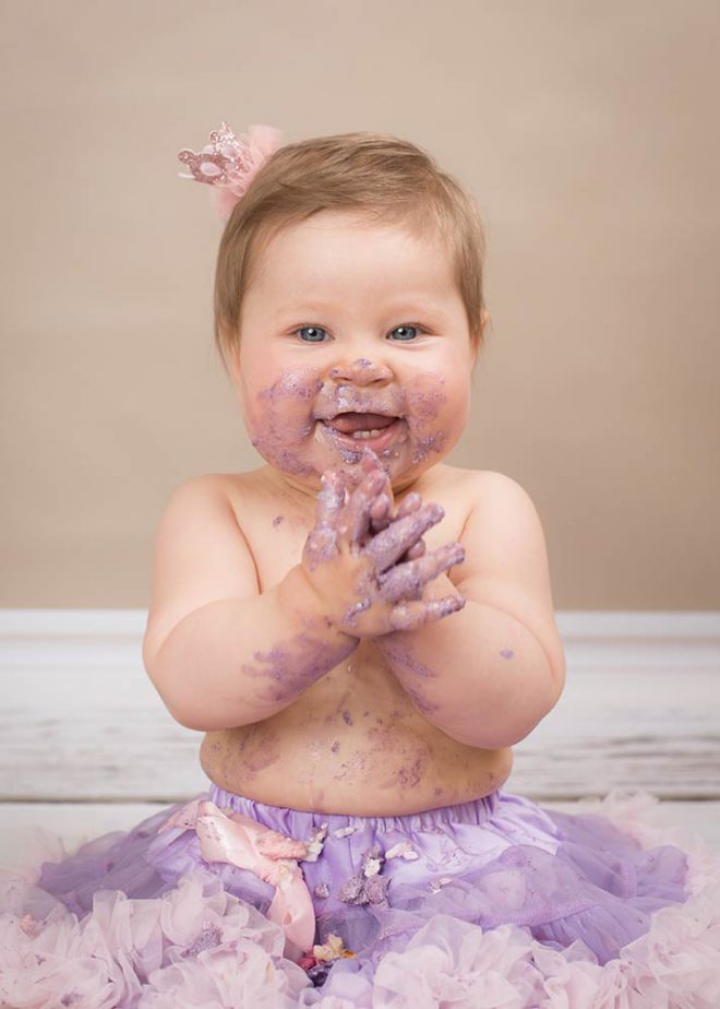 Cake Smash Fotos Berlin: Mädchen mit kuchenverschmiertem Mund klatscht beigeistert in die Hände