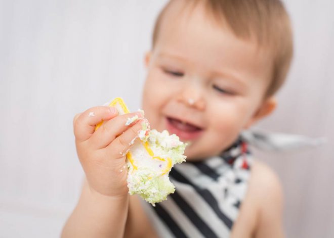 Junge schaut mit Kuchen verschmierte Geburtstagskerze 1 an