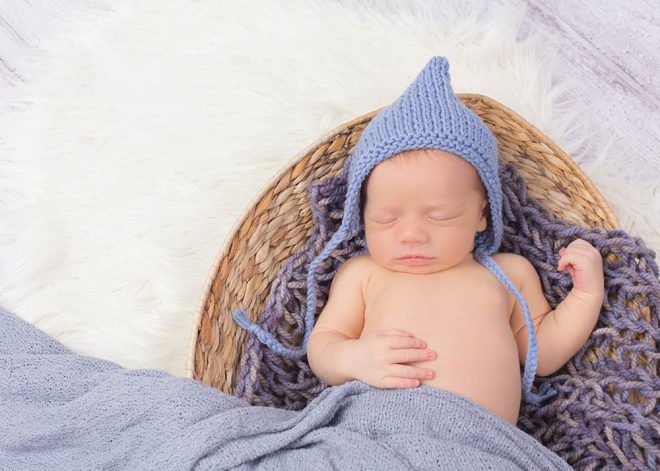 neugeborener Junge mit blauer Strickmütze in Korb