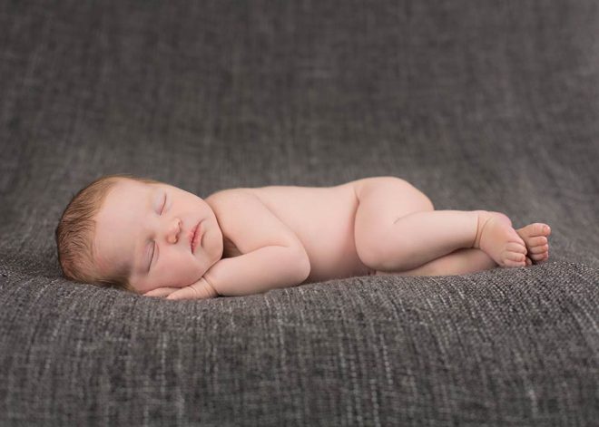 schlafendes Baby auf dunkelgrauer Decke in Seitenlage