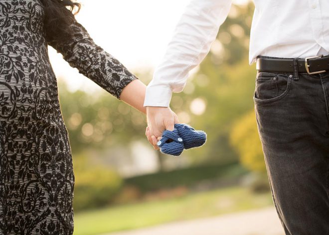 Paar hält gemeinsam ein Paar Babyschuhe