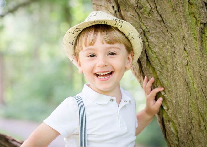 Kinderfotos Berlin: Lachender Junge sitzt auf einem Baum