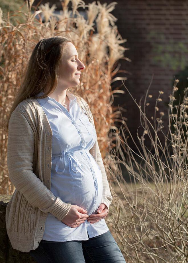 Babybauch Shooting im Winter: Frau genießt die Sonne