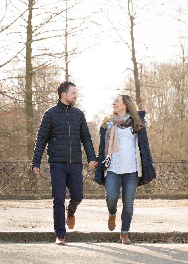 Schwangeres Paar spaziert im Winter durch den Park