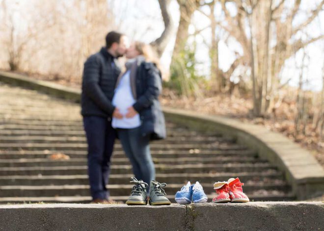 Babybauch Shooting im Winter: Werdende Eltern küssen sich auf einer Treppe