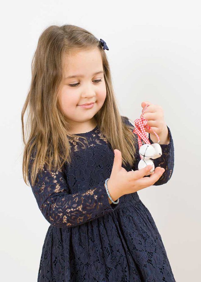 Minimalistische Weihnachtsfotos: Mädchen in blauem Kleid mit Glöckchen in der Hand