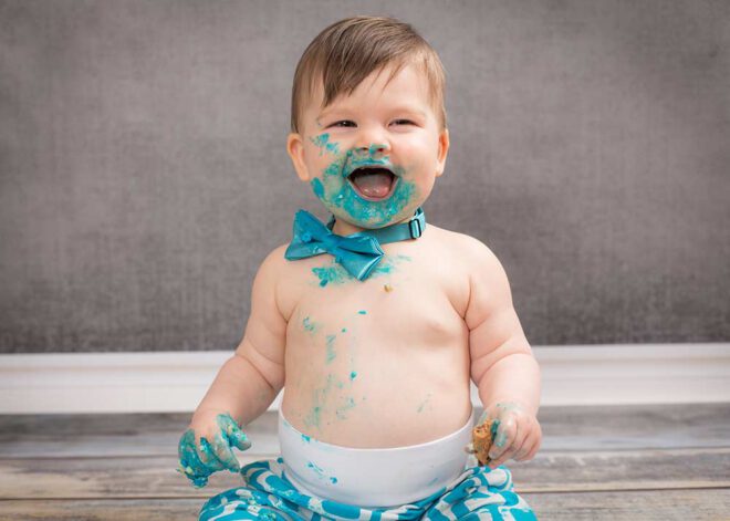 Junge mit blauer Fliege und blau verschmiertem Mund lacht
